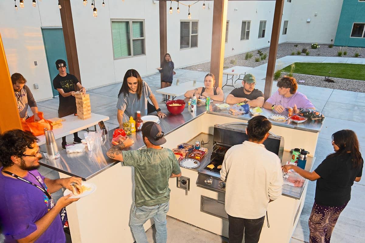 SJC的学生们在学生宿舍的户外烧烤架上闲逛，享受游戏和食物..